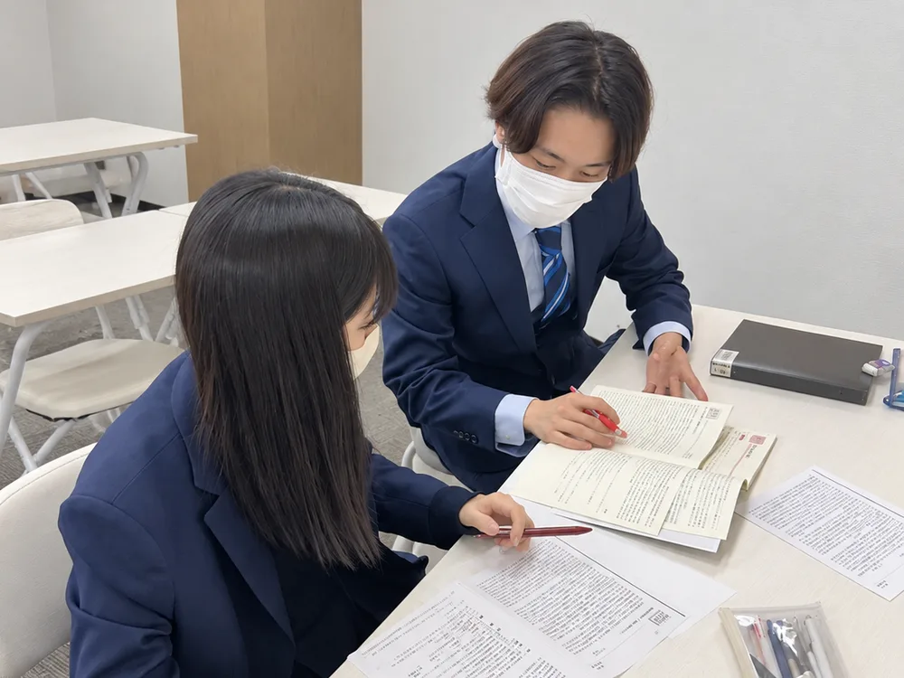 講師が生徒の手元をすぐ横で見ているシーン